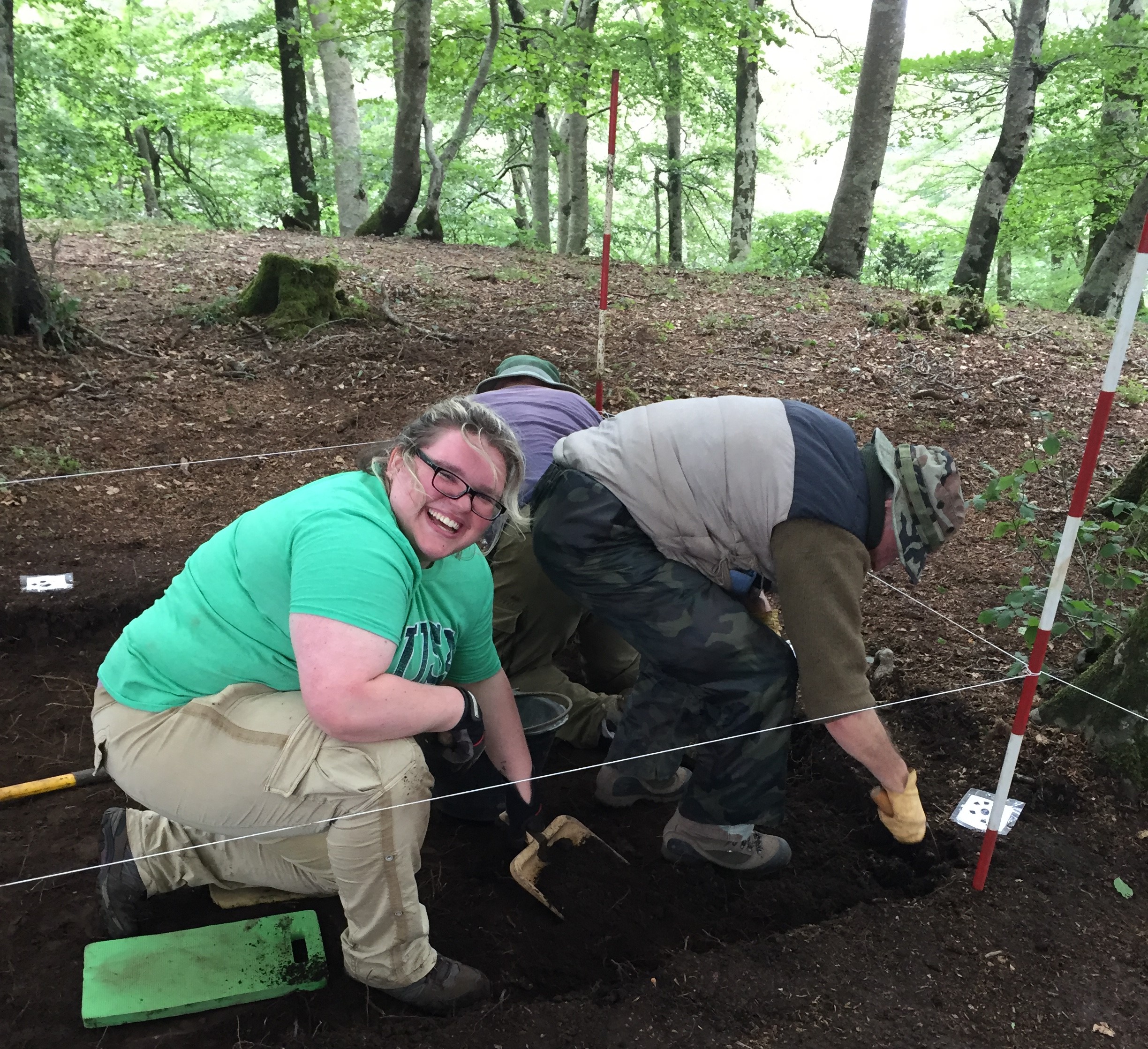 a woman participating in an archaeological excavation looks up from a trench