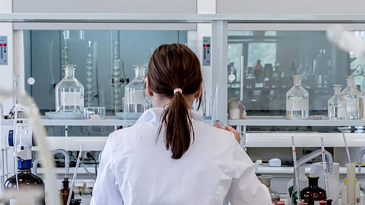 A woman conducts research or technical support in a fully equipped laboratory.