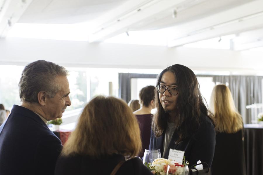 A student and two Langara donors standing and chatting at a table.